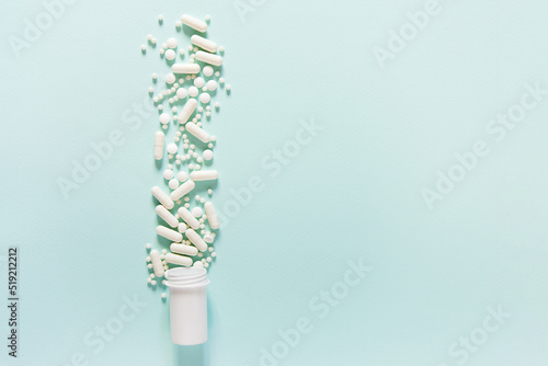 Scattered white pills on blue table. Mock up for special offers as advertising, web background or other ideas. Medical, pharmacy and healthcare concept. Copy space. Empty place for text or logo © Olena Svechkova