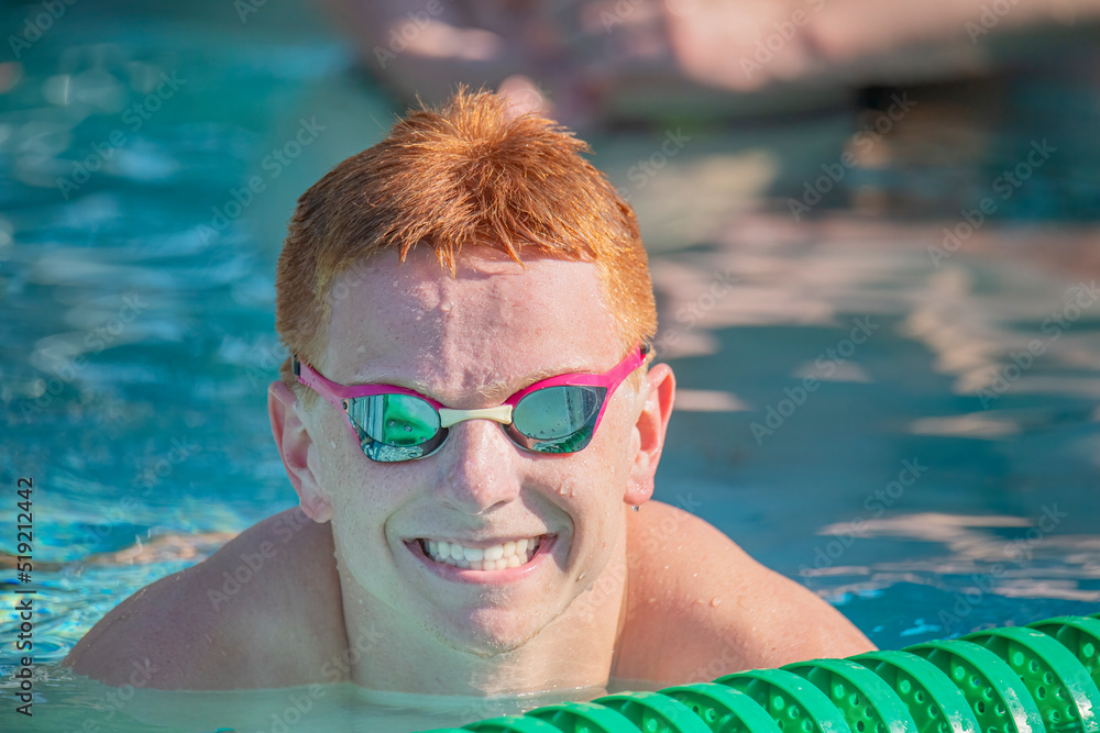 Young man with red hair and big smile in a swimming pool