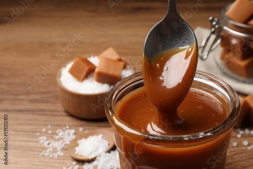 Taking tasty salted caramel with spoon from glass, closeup. Space for text