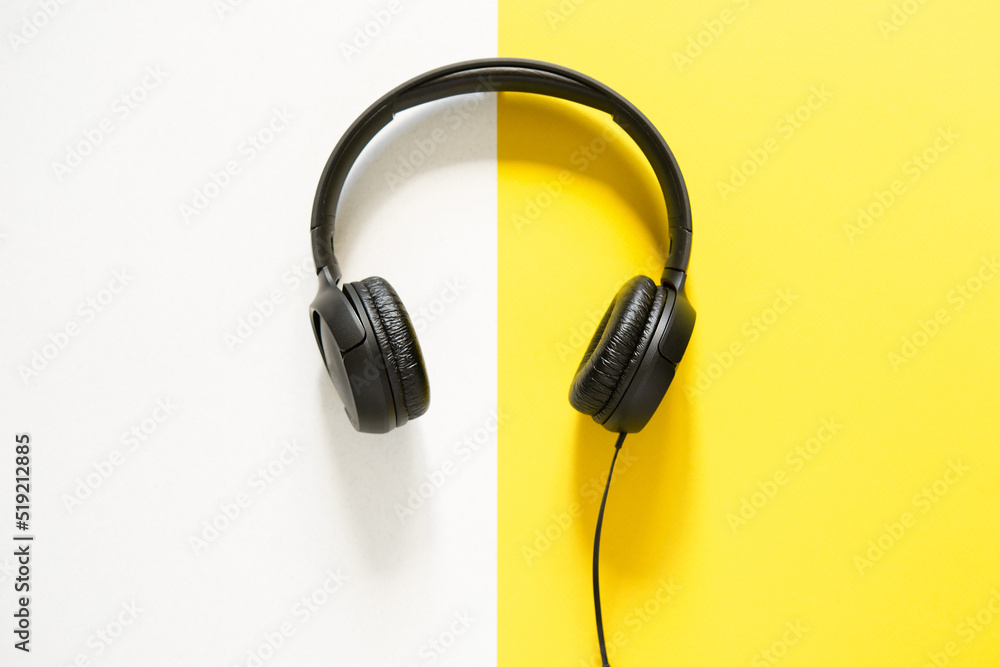 Hands holding headphones on a bicolor yellow and white background. view from above. copy space Hands holding headphones on a bicolor yellow and white background. view from above. copy space