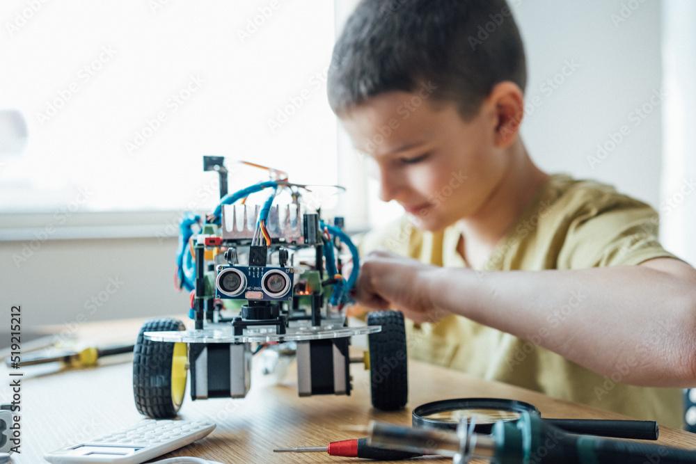 Close up shot of a young boy concentrating repairing his electronic robot toys while playing, building, creating electronics robotics technology. Scientific, education, hobby, lifestyle concept