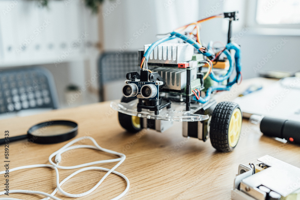 Metal robot for the constructing standing at the table. A lot of boards and microcontrollers are on the table. Programming, mathematics, science, technologies, DIY concept