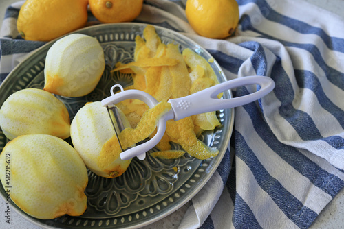 Lemon fruits and peeled strips for zest or making limoncello. Peeler, lemons and zest. Copy space, selected focus photo