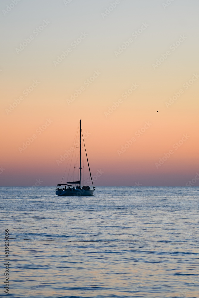 Sailboat against the backdrop of the sunset sky in the sea.