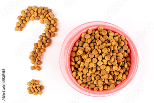 Pink bowl with dry food for a cat (dog) and a question mark on a white isolated background. Feed quality, diet, norms. Balanced nutrition of pets.