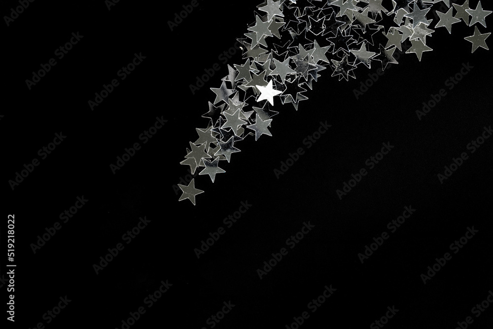 Falling down silver stars on a black background. The concept of a Christmas star and starfall. The concept of holiday magic and Christmas mystery. copyspace.