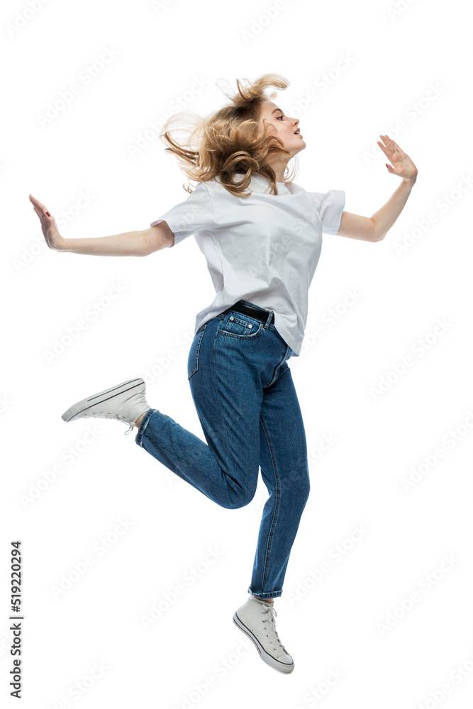 A cute young girl is jumping. A teenager in a white T-shirt and blue jeans. Activity and positive. Isolated on white background. Vertical.
