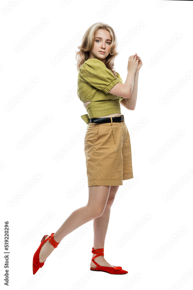 A cute young teen girl in beige shorts and a green blouse is standing. Isolated on white background. Vertical A cute young teen girl in beige shorts and a green blouse is standing. Isolated on white background. Vertical