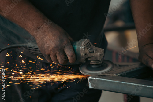 Close up on a man held an angle grinder to cut an iron with sparks