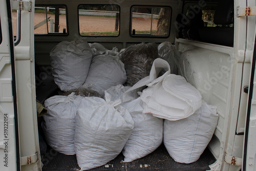 White raffia bags containing agricultural inputs for the garden, stored and arranged in the body of an old white transport car known as a kombi, van, or pickup truck. © Thatha.Luz