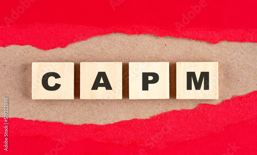 CAPM word on wooden cubes on red torn paper