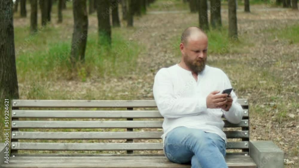 A young man in the summer in the park communicates on the phone. A young man in the summer in the park communicates on the phone.