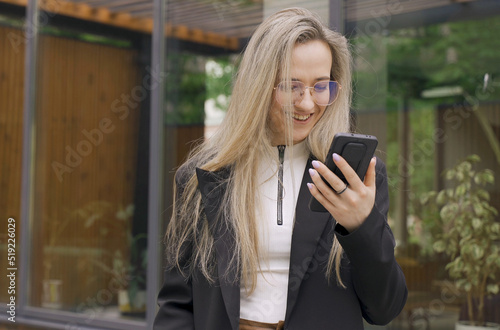 The girl reads a message on a smartphone, smiles and rejoices.
