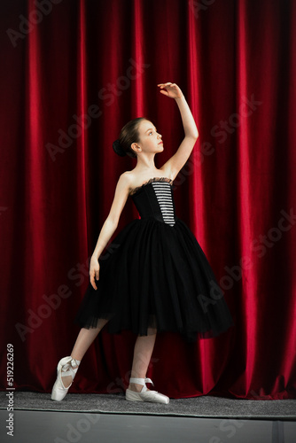 A cute ballerina girl in a black dress on a red background. Art. Dance. Beauty. © Natalya Temnaya