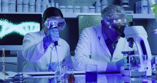 Two laboratory scientists testing phenolphthalein chemical reaction with a petri dish and pipette in ultraviolet lab. Serious doctors wearing protective glasses, experimenting alkaline presence test photo