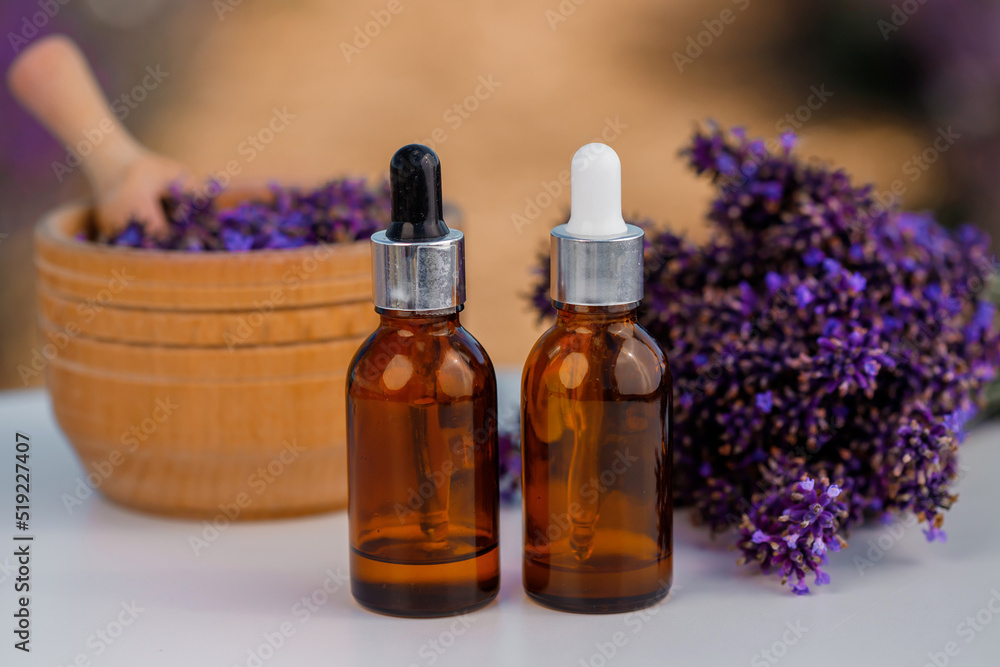 Dropper bottle with lavender cosmetic oil or hydrolate against lavender flowers field as background with copy space. Herbal cosmetics and modern apothecary concept Dropper bottle with lavender cosmetic oil or hydrolate against lavender flowers field as background with copy space. Herbal cosmetics and modern apothecary concept
