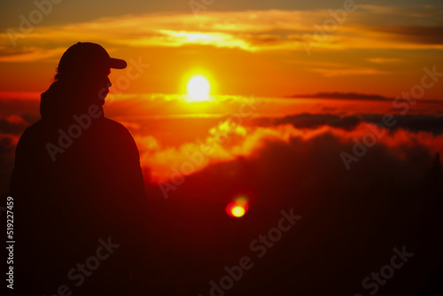 Young man looking sunset over the clouds