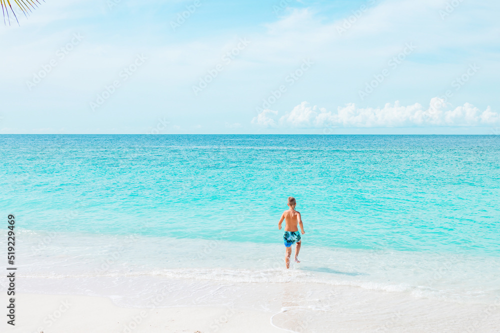 cute boy run along the beach in the Maldives, a travel concept cute boy run along the beach in the Maldives, a travel concept