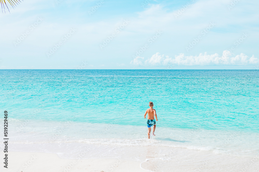 cute boy run along the beach in the Maldives, a travel concept