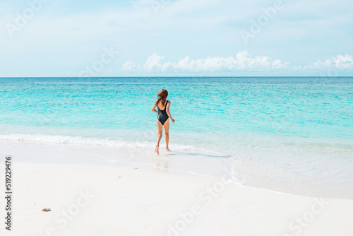 teenage girl with red hair in swimsuit run along the beach in the Maldives, a travel concept