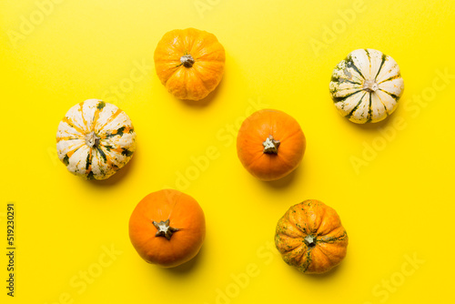 Autumn composition of little orange pumpkins on colored table background. Fall, Halloween and Thanksgiving concept. Autumn flat lay photography. Top view vith copy space