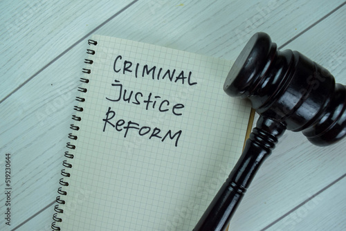 Concept of Criminal Justice Reform write on a book with gavel isolated on Wooden Table. photo