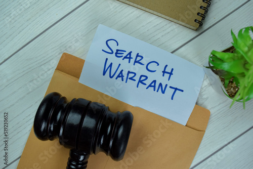 Search Warrant text on document above brown envelope with gavel.