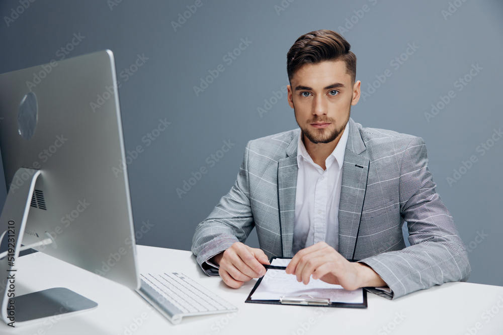 businessmen in a gray suit sits in front of a computer technologies businessmen in a gray suit sits in front of a computer technologies