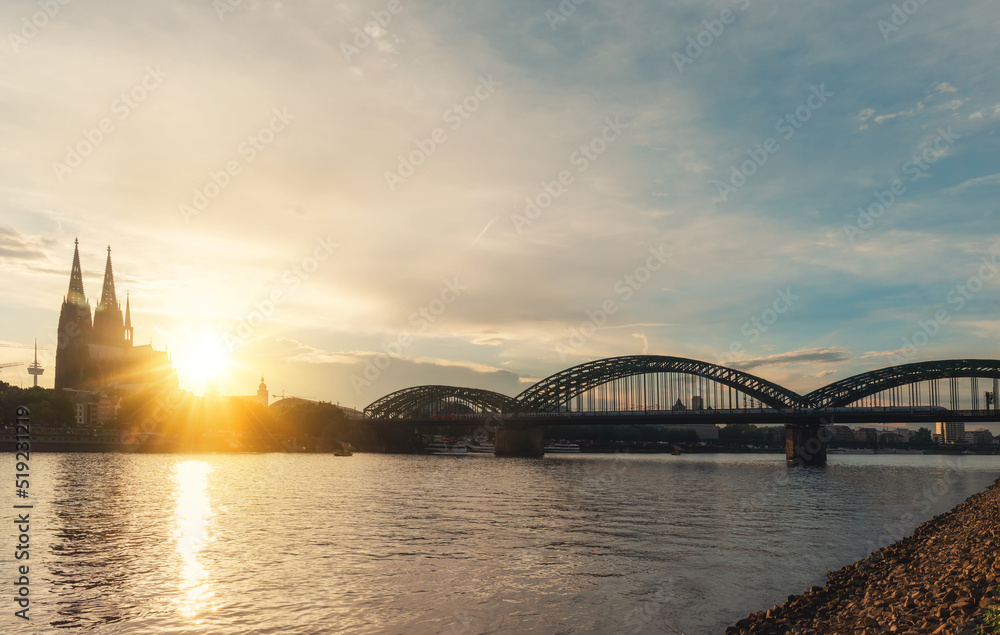 Fototapeta premium embankment of Rhine on background of Cologne Cathedral and Hohenzollern Bridge in Cologne Koel, Germany at sunset. Tourism and travel by Germany..