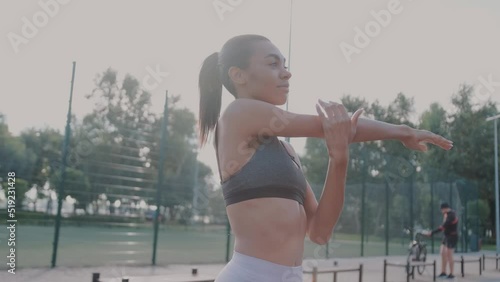 Healthy anf active lifestyle. Sports and fitness. Happy African woman in sportclothes working out on the sports ground in sunny summer day, warming up photo