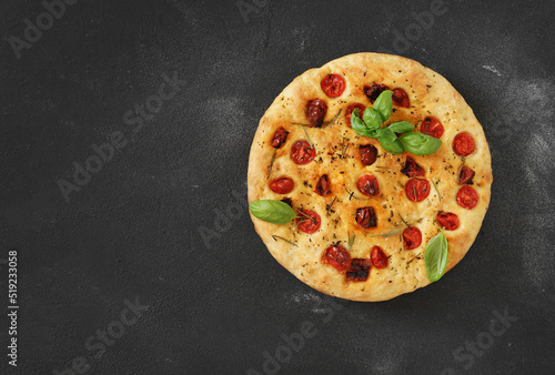 Traditional Italian Focaccia with tomatoes and rosemary on the dark background - homemade. Copy space.