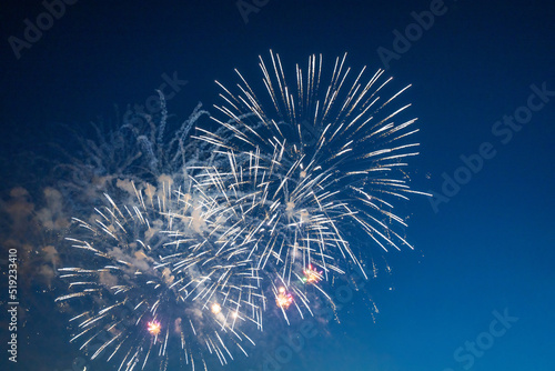 Firework over the blue sky at night, white and red. Amateur photo. Noise. Grain