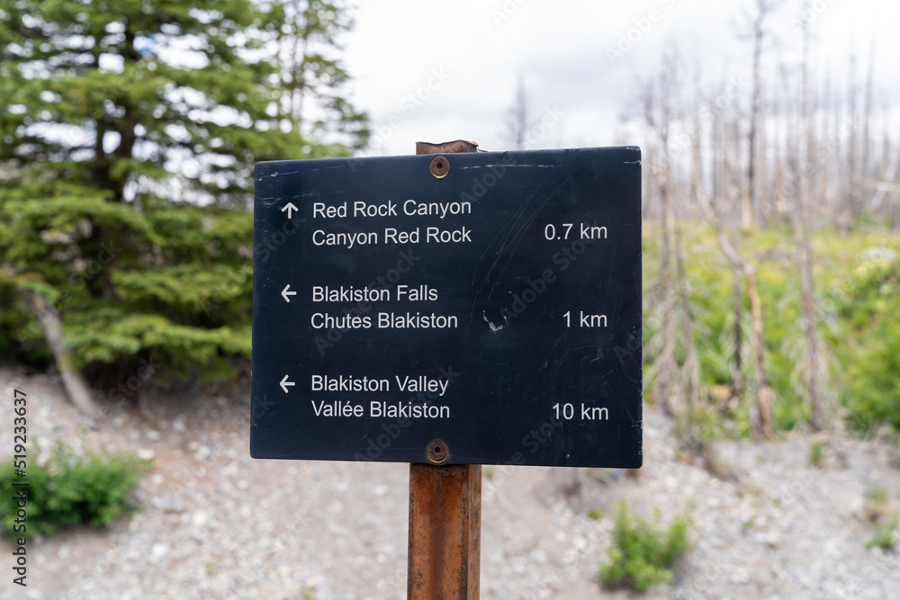 Sign for various trail lengths for hiking trails in the Red Rock Canyon Parkway in Waterton Lakes National Park Canada. Includes Blakiston Falls and Valley