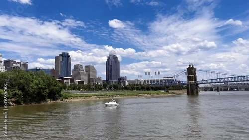 CINCINNATI, OHIO. the John A Roebling steel suspension bridge over the Ohio River in Cincinnati, Ohio. The boat passes in the foreground. High quality FullHD footage