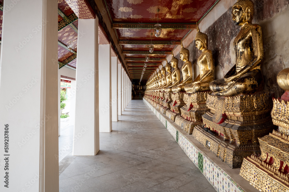 Fototapeta premium Row of buddha statues along corridor of Wat Suthat Thepwararam Ratchaworahawihan temple in Bangkok, Thailand 