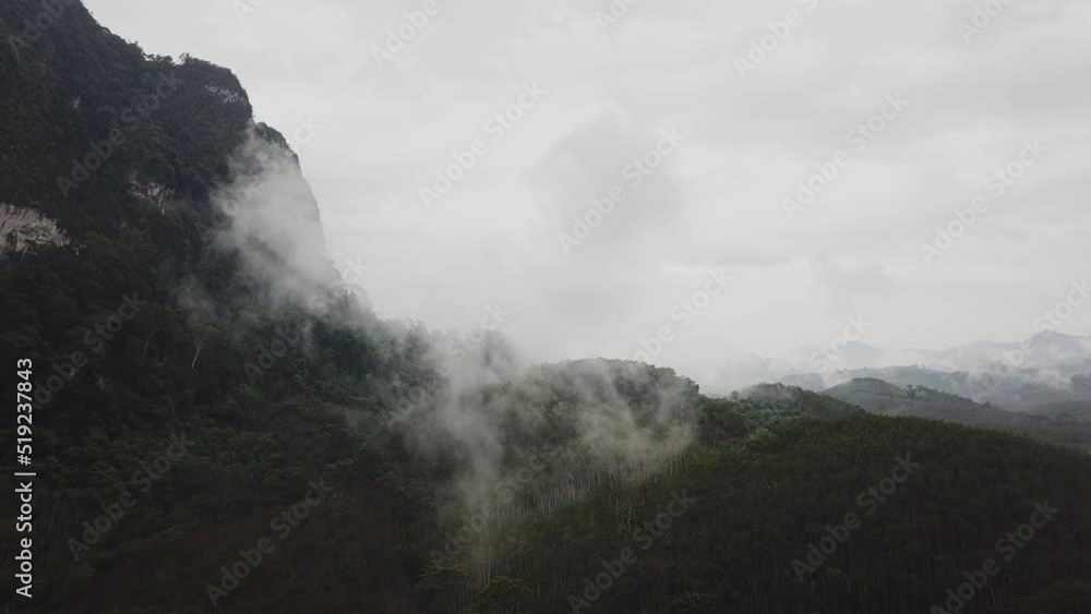 Flying near the mountains above tropical rainforest with mist, clouds on a rainy day. Thailand Flying near the mountains above tropical rainforest with mist, clouds on a rainy day. Thailand