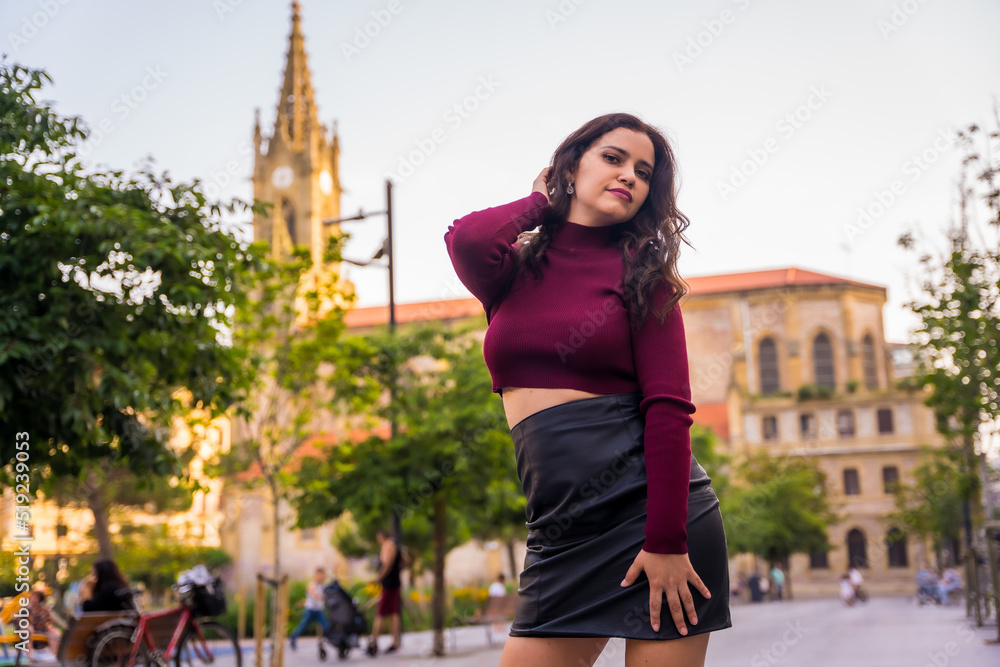 Portrait of a brunette Latin woman with a leather skirt next to a church visiting the city, lifestyle