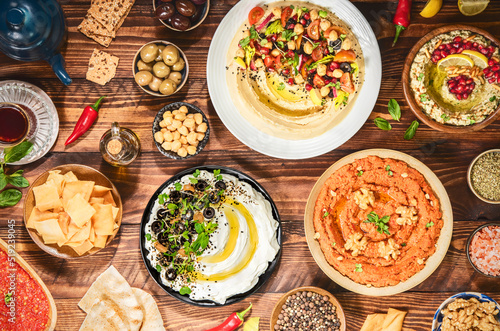 Arabic Cuisine: Varieties of delicious Middle Eastern meze and dips. hummus plate, muhammara, labneh, baba ghanough, harissa and olives. Served with pita bread and fresh olive oil. photo