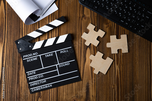 black movie clapper with keyboard and script sheets on a wooden table photo