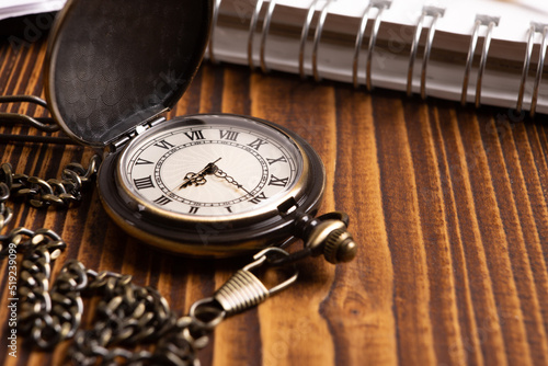 pocket watch with notepad on wooden background closeup concept