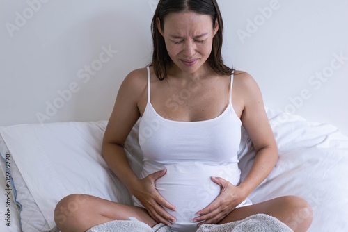 A pregnant woman holding her stomach in pain and discomfort. Contractions and cramps.