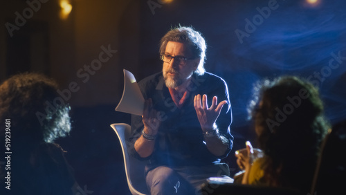 Photo Mature director on a dim theater stage talking to the actor and disabled actress