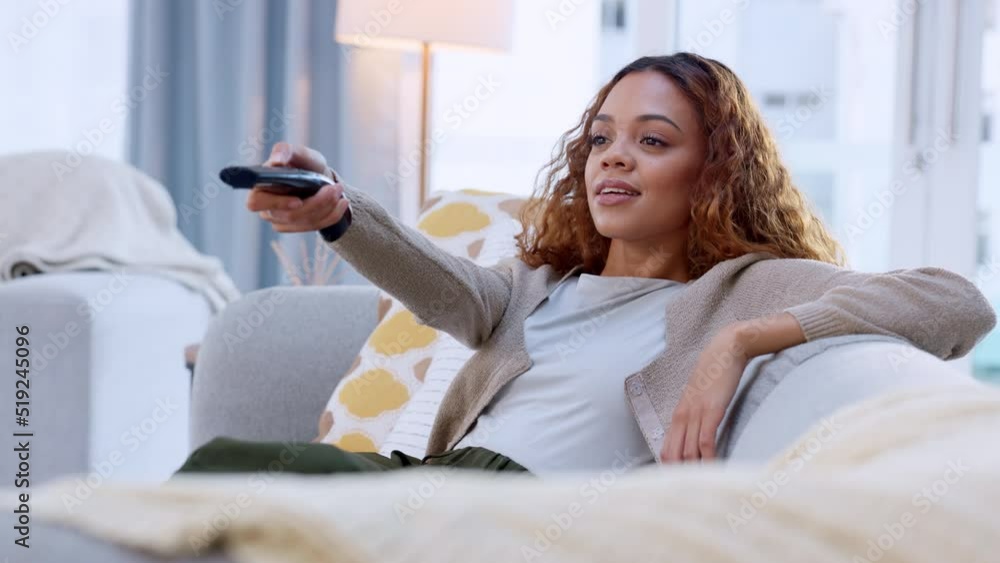 Female enjoying her favorite movie or favorite comedy TV show, anticipating the next scene. Changing the channel with a remote control. Laughing woman watching the news, sitting on a couch at home Female enjoying her favorite movie or favorite comedy TV show, anticipating the next scene. Changing the channel with a remote control. Laughing woman watching the news, sitting on a couch at home