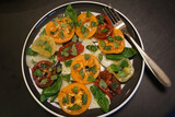 Healthy, appetizing Italian caprese salad on a plate, with multicolor heirloom tomatoes, fresh basil, and mozzarella cheese.