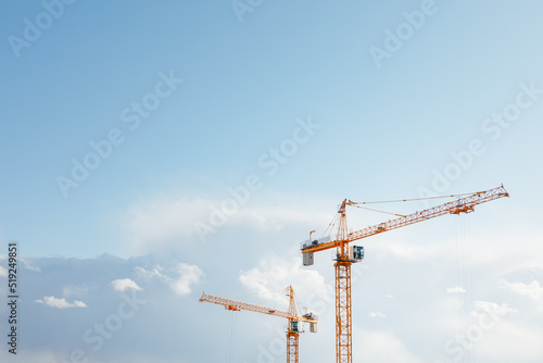 building cranes at the construction site on blue sky background © nikkytok