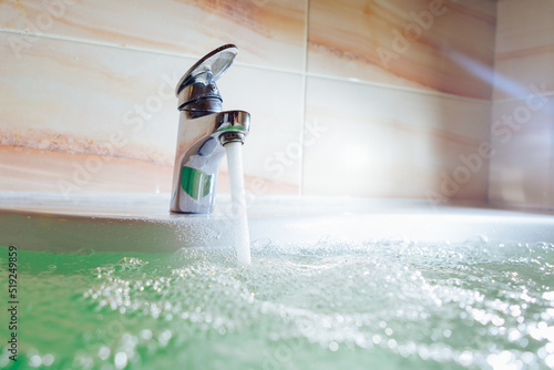 single handle faucet pouring hot water in a bath tub photo