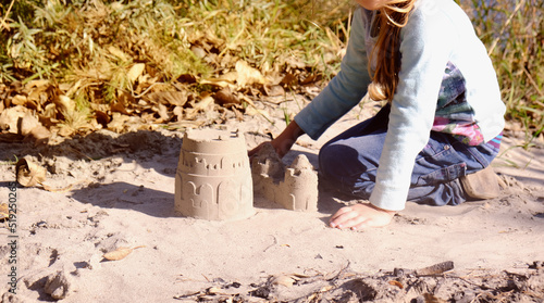 Child building sandcastle, playing with fun on the beach with toys. Autumn or springtime outdoors