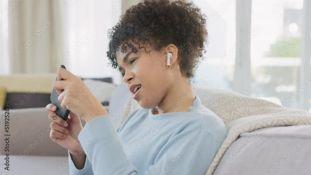 Focused, young female playing a high level mobile game on a phone at home. Portrait of a woman getting points during a digital racing event. Casual gamer plays digital video games with headphones. Focused, young female playing a high level mobile game on a phone at home. Portrait of a woman getting points during a digital racing event. Casual gamer plays digital video games with headphones.