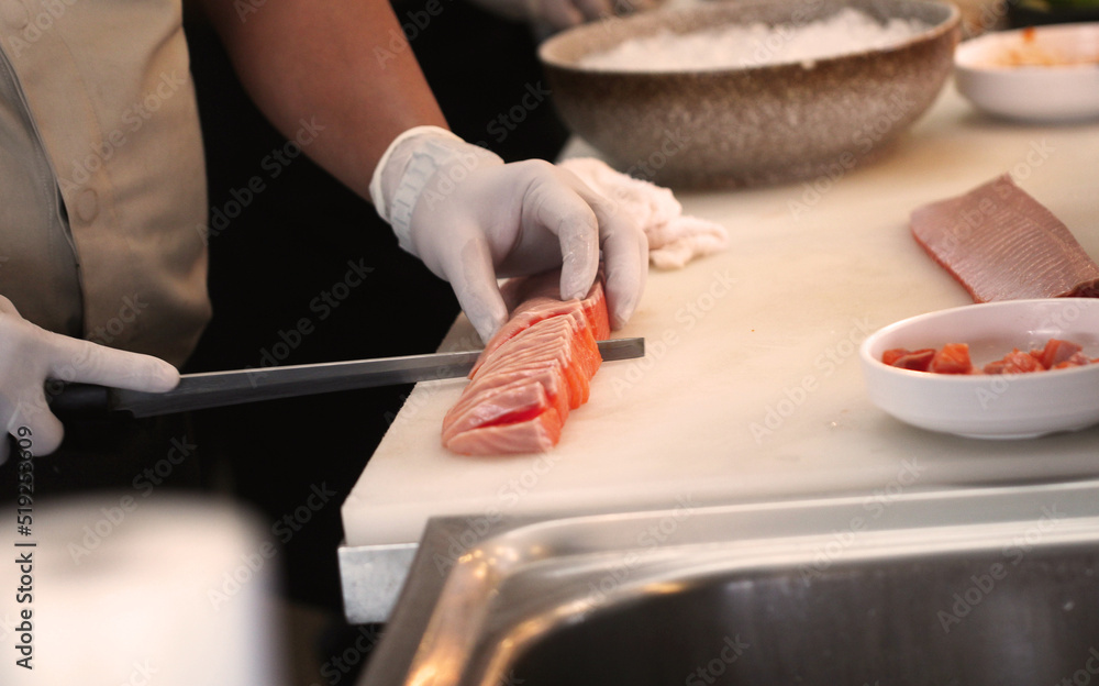 Professional man cut fresh salmon at kitchen of japanese food restaurant. Professional man cut fresh salmon at kitchen of japanese food restaurant.