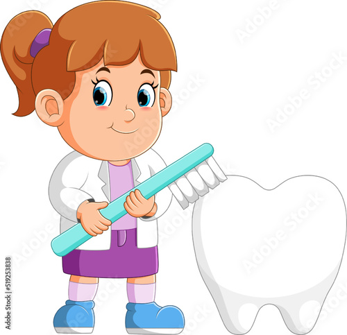The girl dentist is brushing a big white teeth while standing